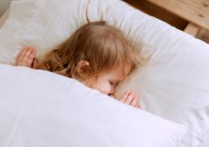 photo of child laying on bed
